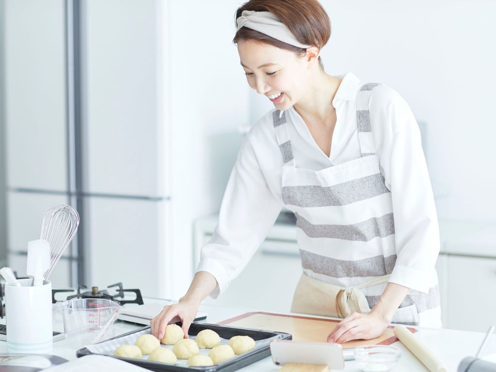 キッチンでパンを楽しそうに作る女性