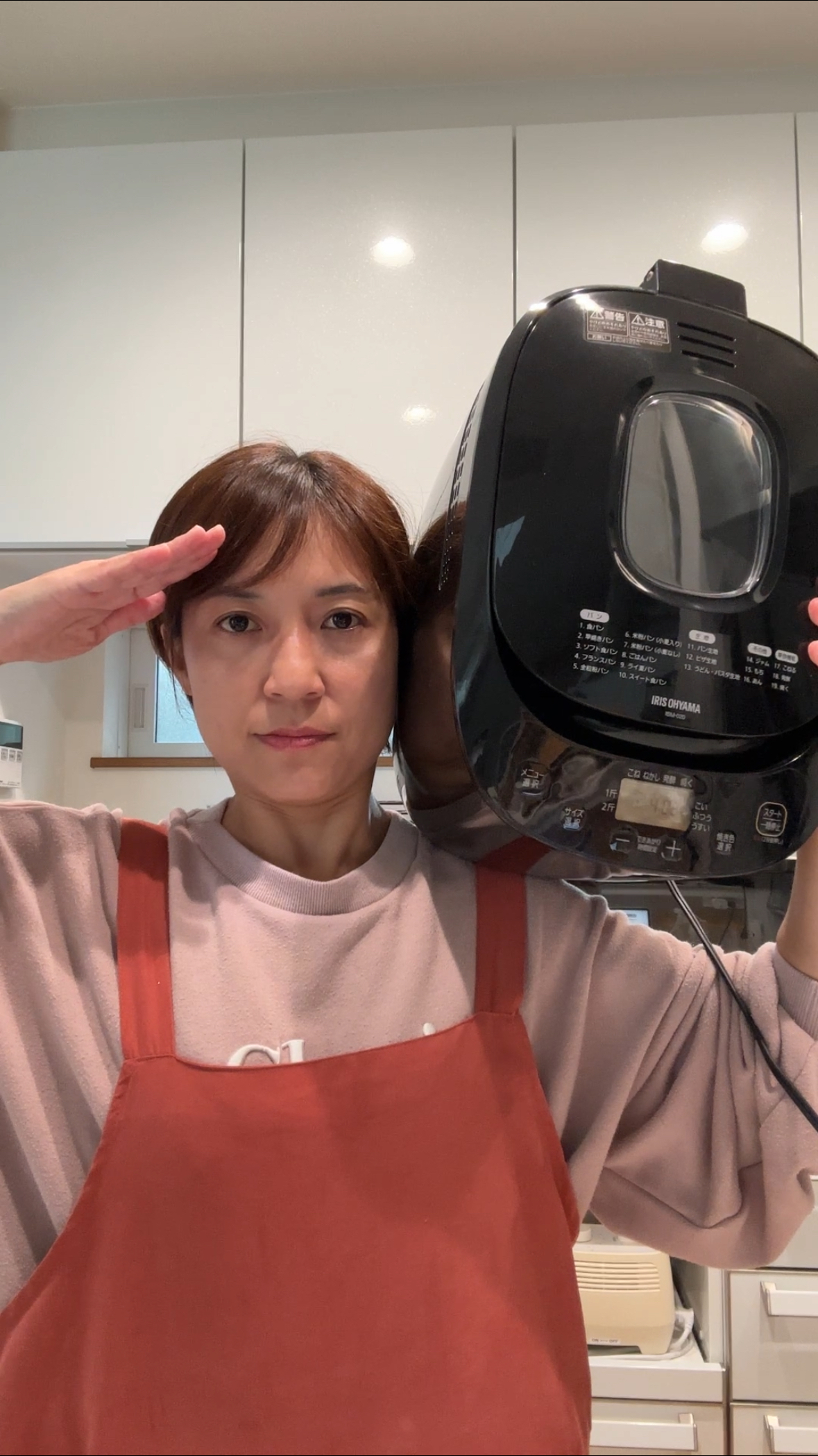 ホームベーカリーを肩に乗せて敬礼する講師